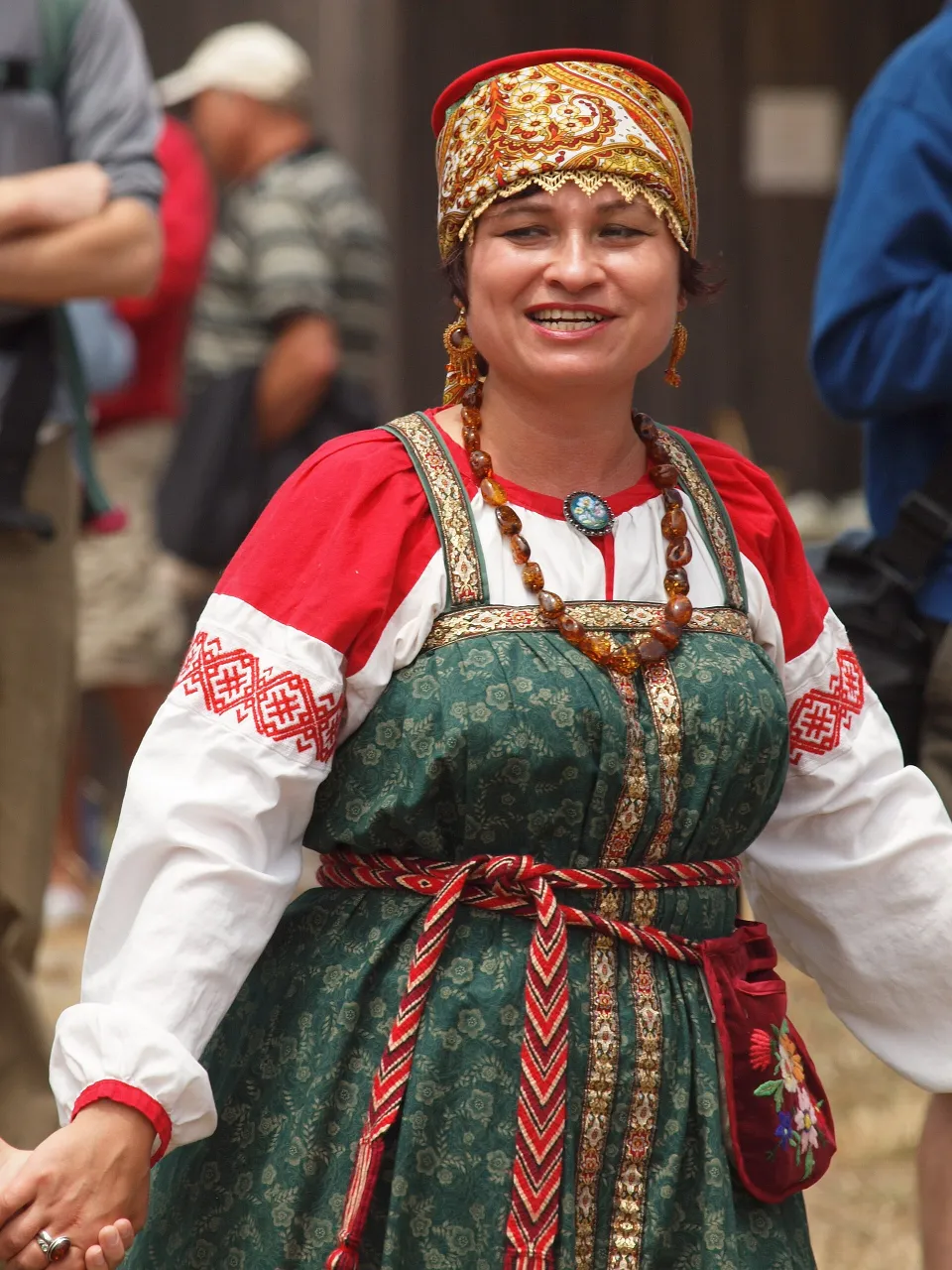 Женщина в кокошнике, белой рубахе с красной вышивкой и зелёном сарафане
